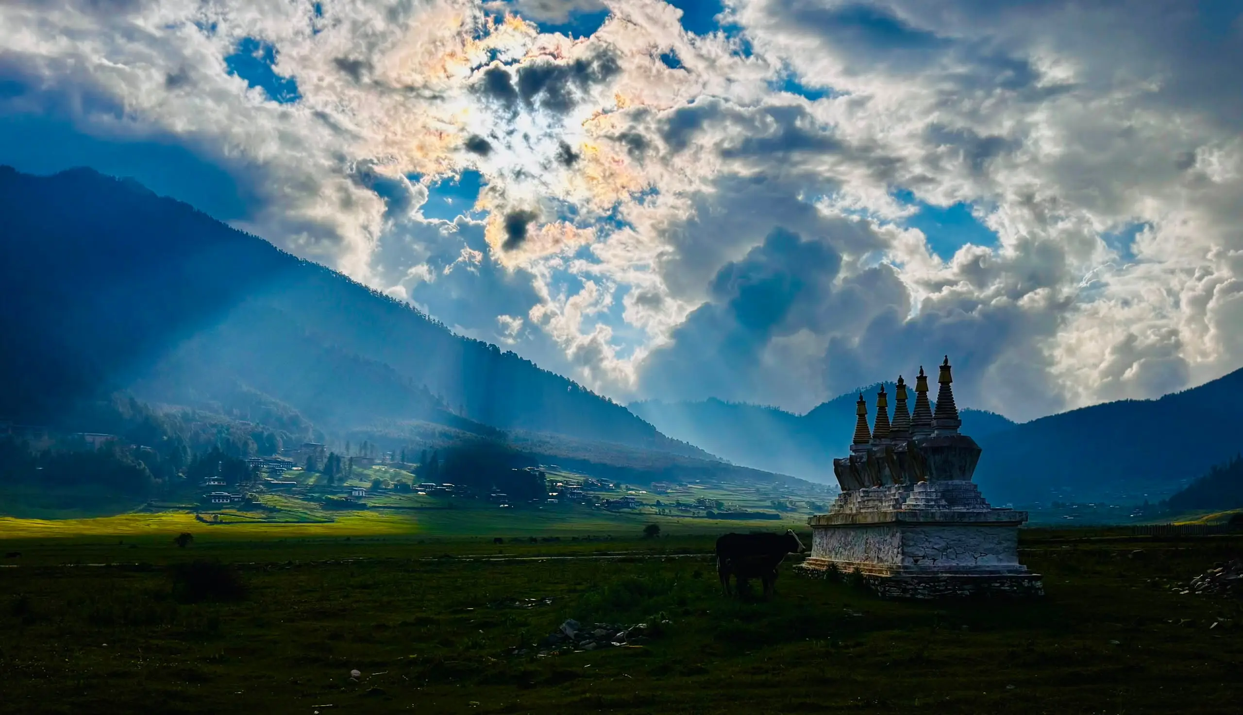 Chortens on the wide floor of the Phobjikha valley, sunbeams breaking over the surrounding ridges